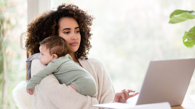 new mom holding baby while emailing